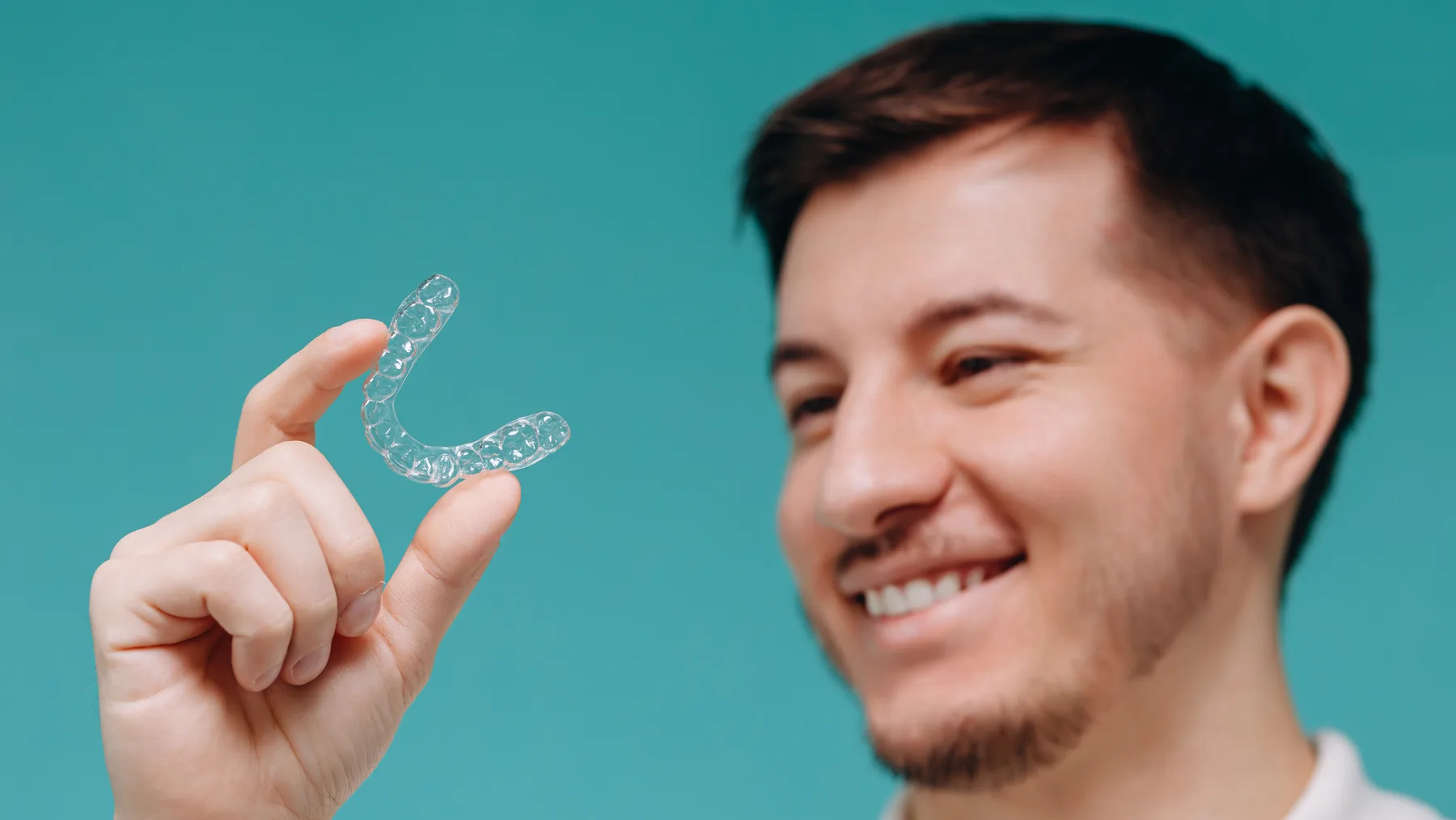 Adult patient holding a clear aligner for discreet orthodontic treatment