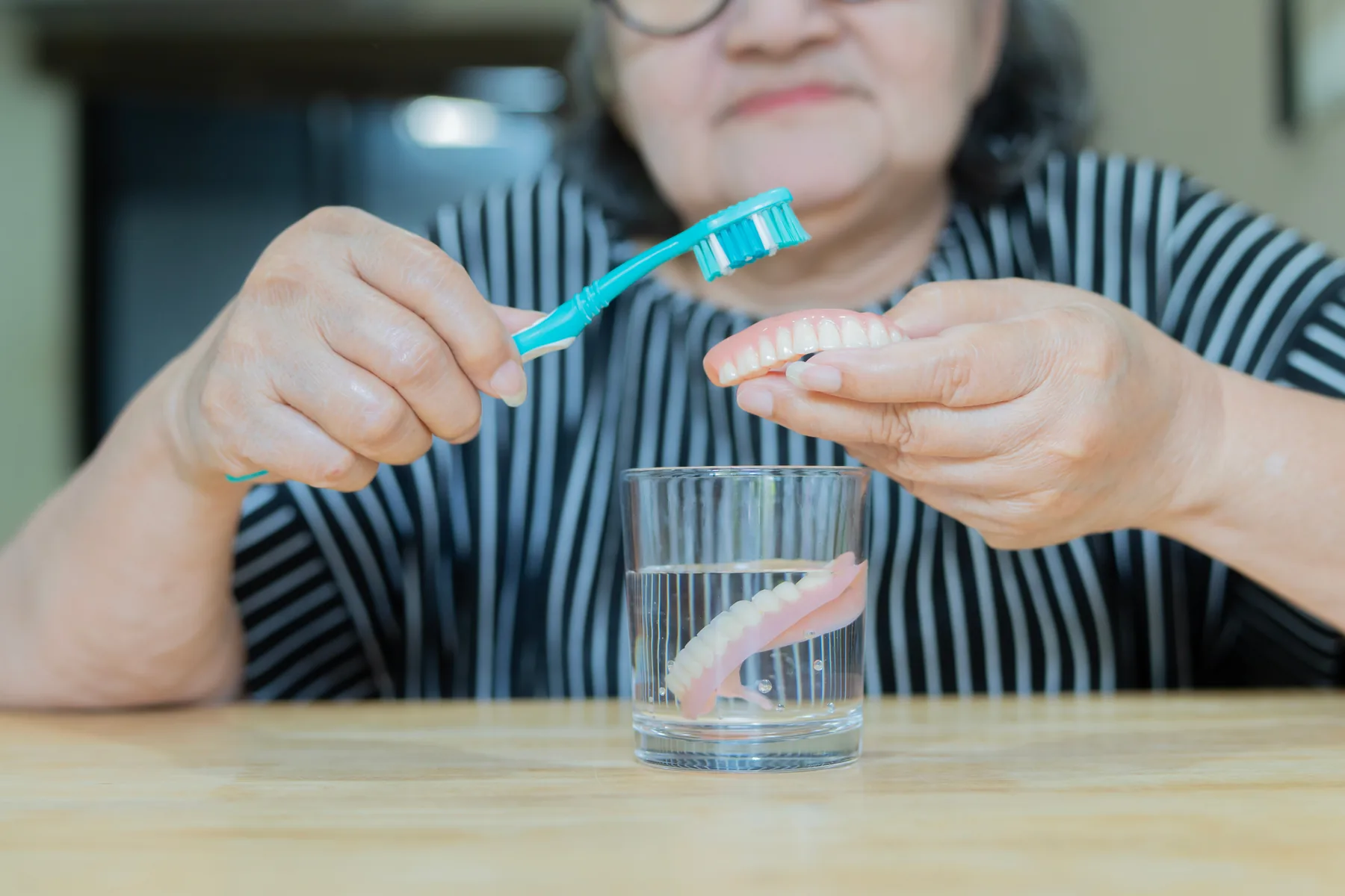 Senior woman caring for her dentures at home
