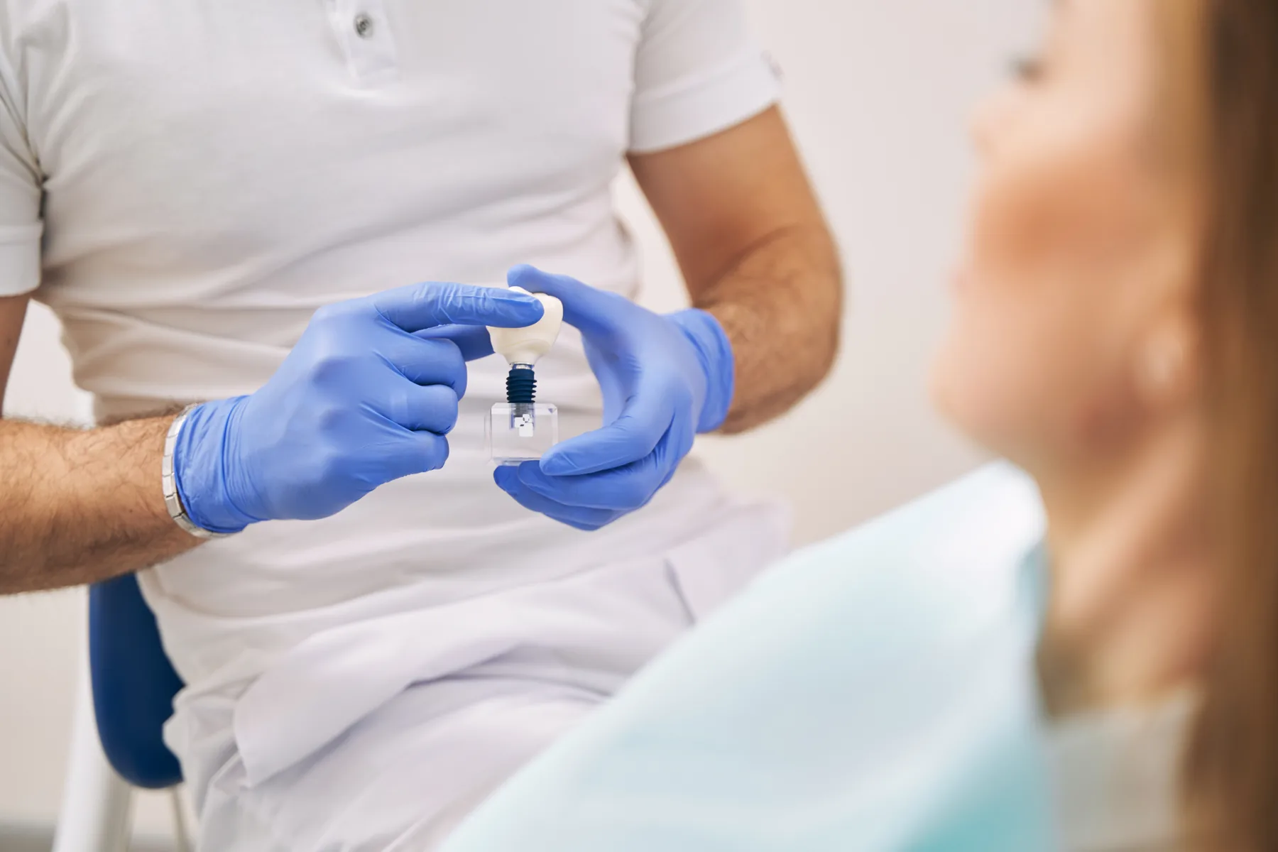 Dentist showing a dental implant model during a patient consultation
