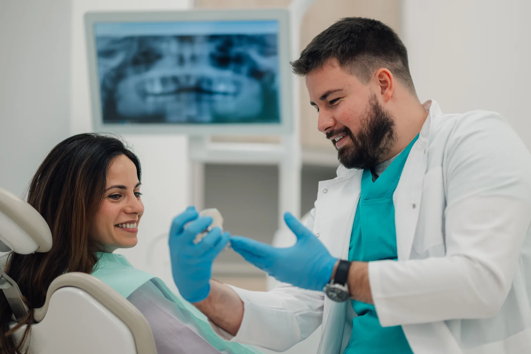 Dentist explaining a teeth model during a patient consultation