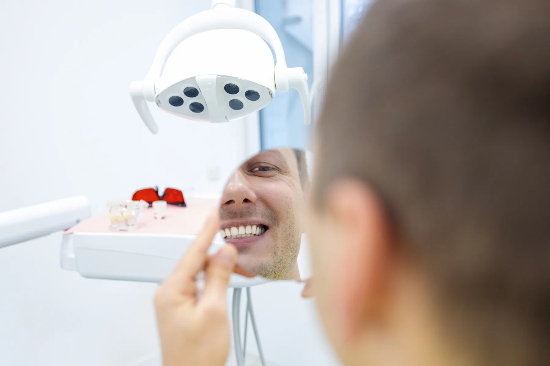 Patient viewing a brighter smile in the mirror after treatment
